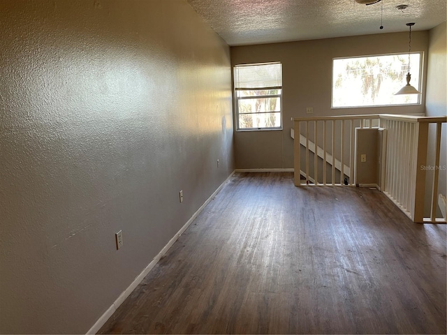 empty room with dark wood-style flooring, baseboards, and a textured ceiling