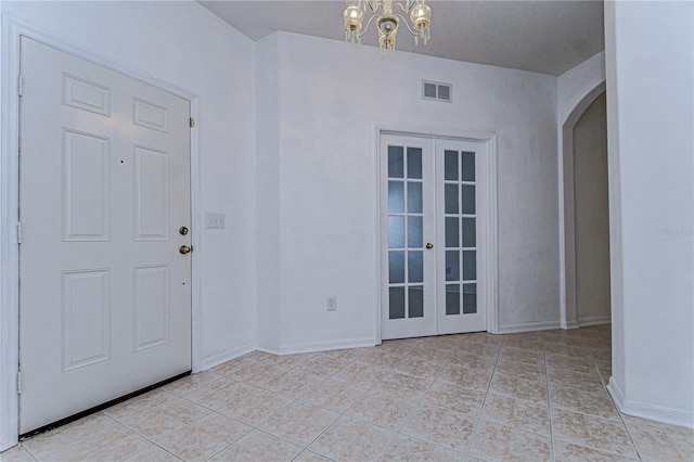 tiled foyer entrance with french doors and an inviting chandelier