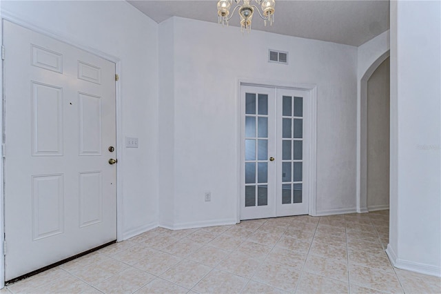 entrance foyer with light tile patterned floors, french doors, and a chandelier