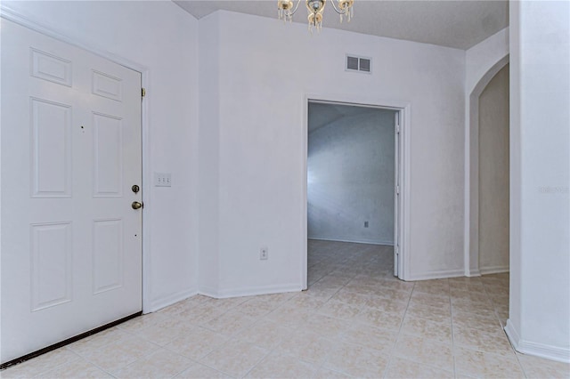 tiled entrance foyer with a chandelier