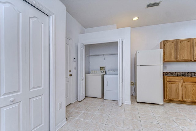 clothes washing area featuring light tile patterned floors and washing machine and clothes dryer