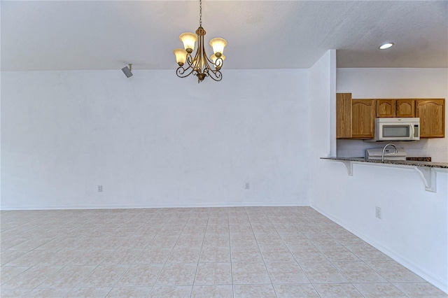 kitchen with range, decorative light fixtures, light tile patterned floors, and an inviting chandelier