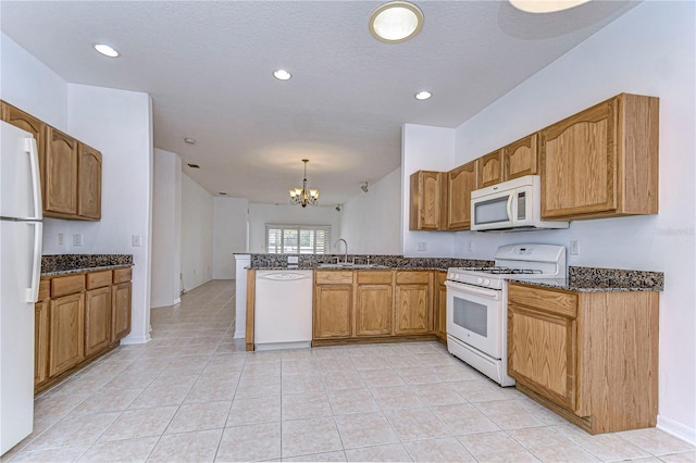 kitchen with white appliances, an inviting chandelier, sink, hanging light fixtures, and kitchen peninsula