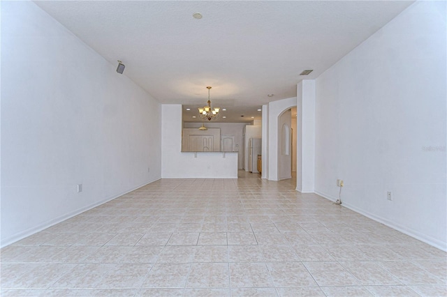 unfurnished living room featuring a chandelier