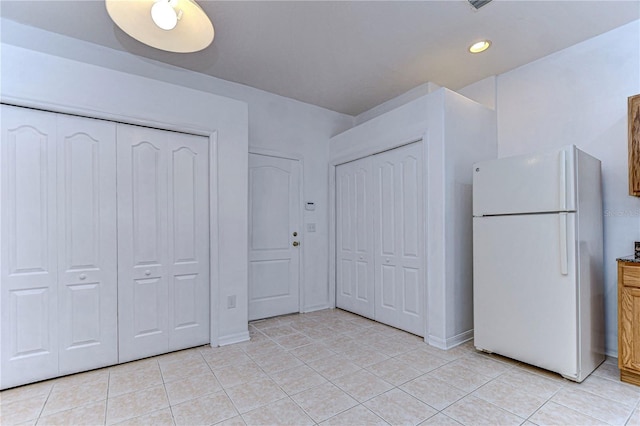 unfurnished bedroom with light tile patterned floors and white refrigerator