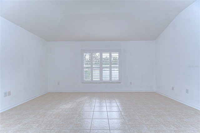 tiled empty room with lofted ceiling