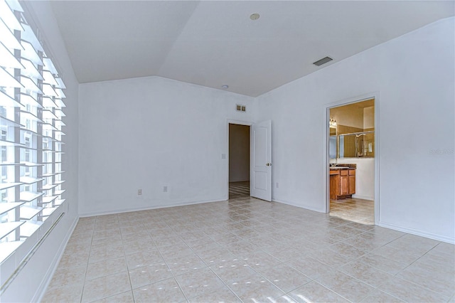 tiled spare room with vaulted ceiling