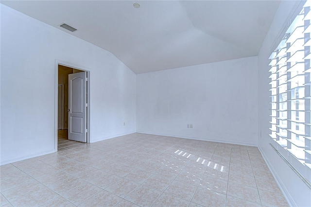 empty room with lofted ceiling and light tile patterned floors