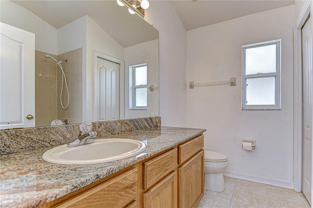 bathroom featuring tile patterned flooring, a tile shower, vanity, and toilet