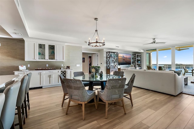 dining area with light hardwood / wood-style flooring, expansive windows, and ceiling fan with notable chandelier