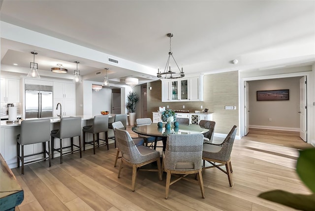 dining room with light hardwood / wood-style flooring, an inviting chandelier, and a tray ceiling