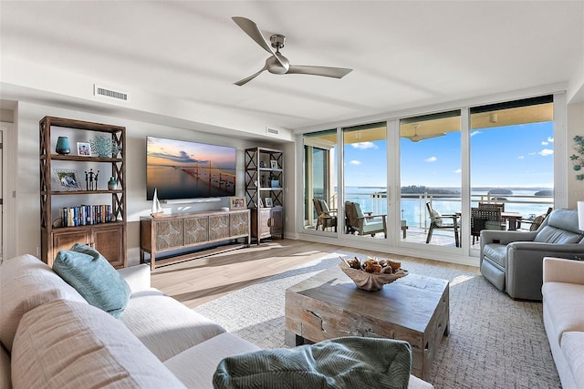 living room with expansive windows, light hardwood / wood-style flooring, and ceiling fan