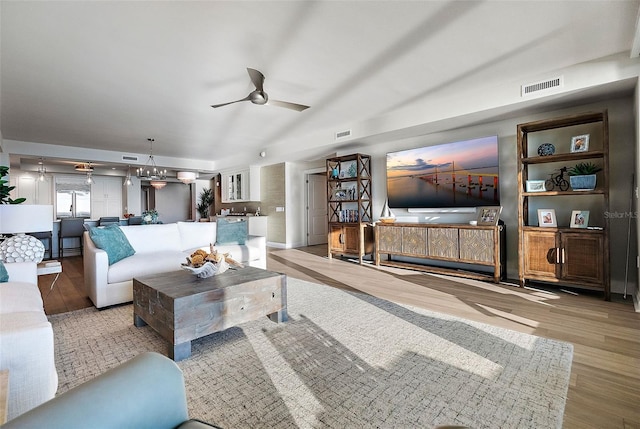 living room with light hardwood / wood-style floors and ceiling fan with notable chandelier