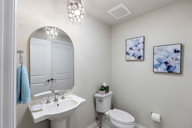 bathroom featuring a notable chandelier, toilet, and sink