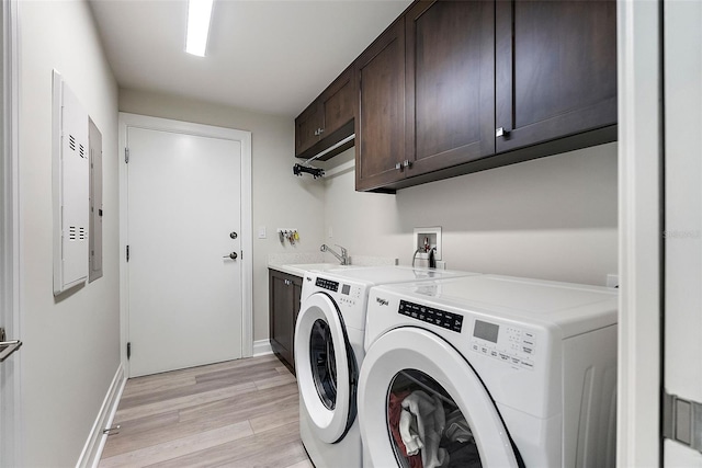 laundry room with cabinets, light wood-type flooring, sink, and washing machine and clothes dryer