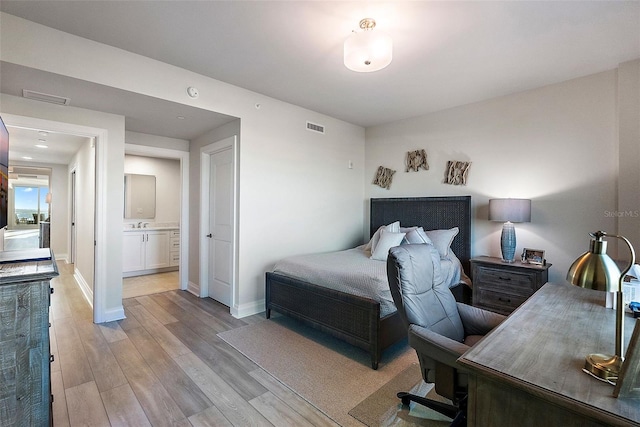 bedroom with light wood-type flooring and connected bathroom