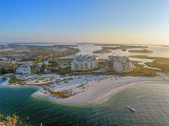 aerial view at dusk with a water view and a beach view