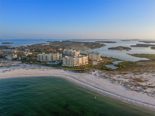 aerial view at dusk featuring a water view and a view of the beach