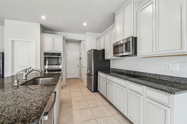 kitchen with stainless steel appliances, sink, white cabinets, and dark stone counters