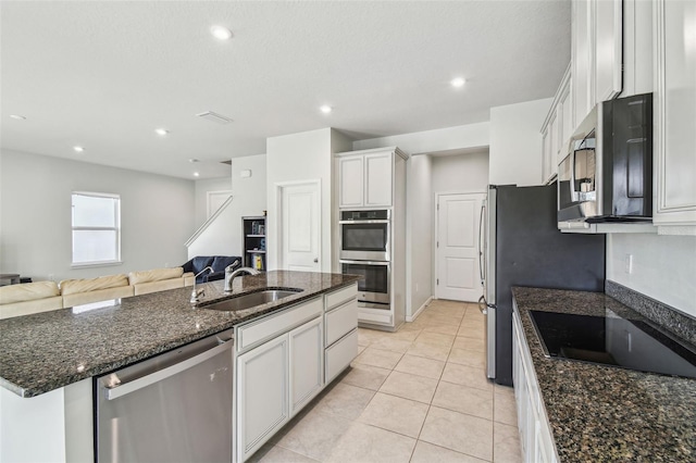 kitchen featuring sink, light tile patterned floors, a kitchen island with sink, stainless steel appliances, and white cabinets