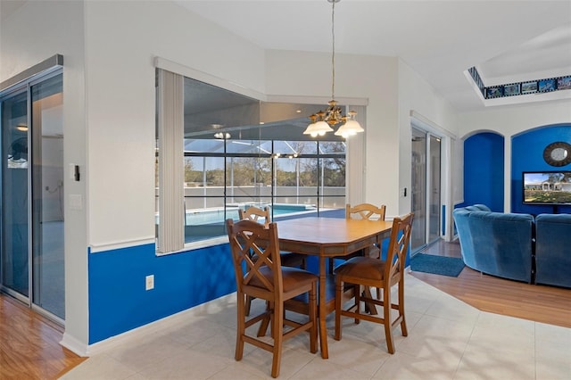 dining room featuring a tray ceiling, light tile patterned floors, and a notable chandelier