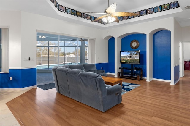 living room with hardwood / wood-style floors, ceiling fan, and a towering ceiling