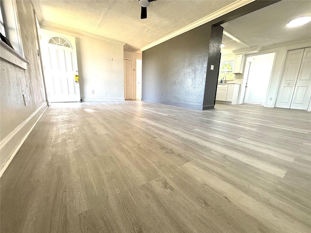 unfurnished living room with light hardwood / wood-style floors, a textured ceiling, crown molding, and ceiling fan