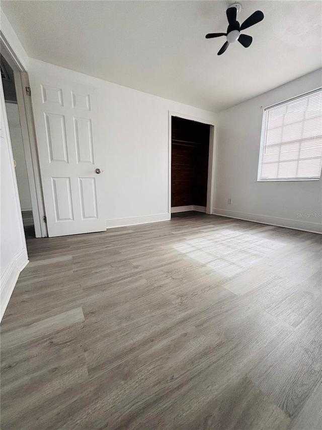 unfurnished bedroom featuring ceiling fan, a closet, and hardwood / wood-style flooring