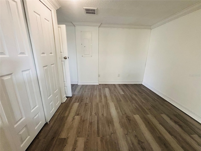 unfurnished room featuring a textured ceiling, dark hardwood / wood-style floors, crown molding, and electric panel