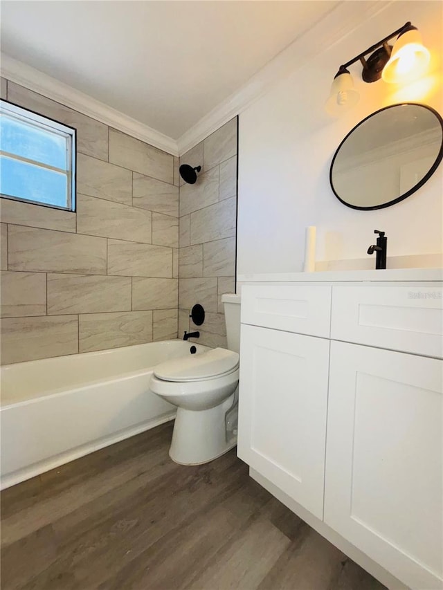 full bathroom featuring toilet, tiled shower / bath, wood-type flooring, ornamental molding, and vanity