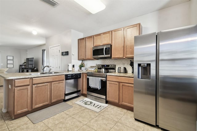 kitchen featuring sink, kitchen peninsula, decorative backsplash, light tile patterned floors, and appliances with stainless steel finishes