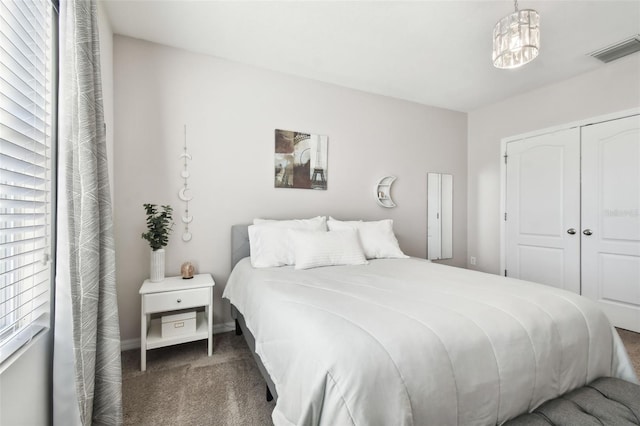 carpeted bedroom with an inviting chandelier and a closet