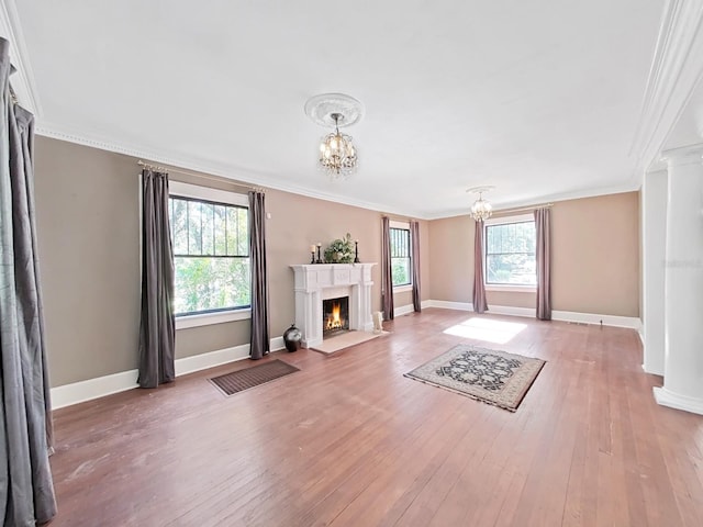 unfurnished living room with a notable chandelier, a healthy amount of sunlight, and crown molding