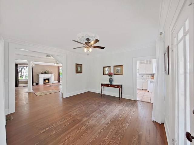 unfurnished living room featuring hardwood / wood-style floors, ceiling fan, crown molding, and decorative columns