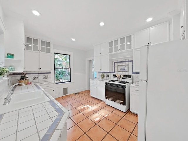 kitchen with white appliances, sink, tile counters, and white cabinetry