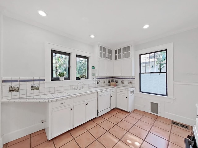 kitchen with light tile patterned floors, white dishwasher, tile countertops, sink, and white cabinetry