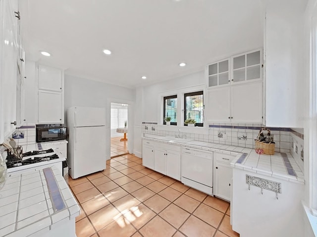 kitchen featuring white appliances, backsplash, tile countertops, white cabinets, and light tile patterned flooring