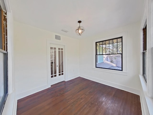 empty room with an inviting chandelier and dark hardwood / wood-style floors