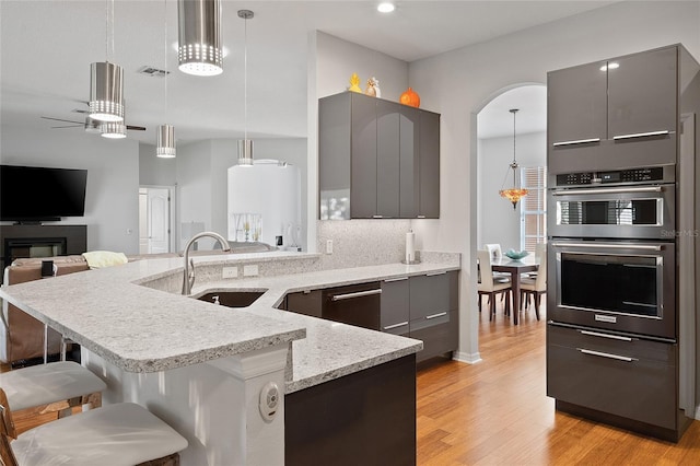 kitchen with gray cabinetry, decorative light fixtures, a breakfast bar area, and appliances with stainless steel finishes