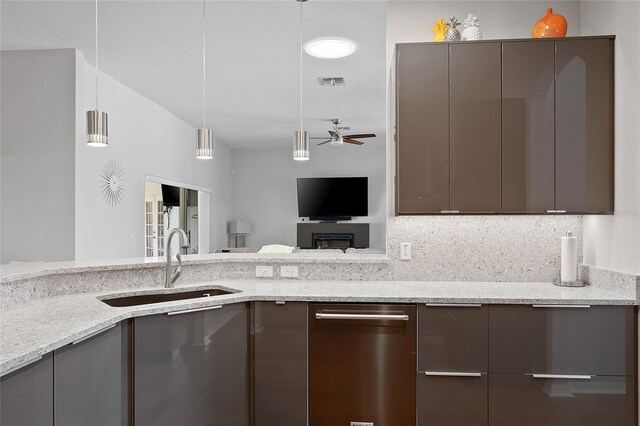 kitchen featuring hanging light fixtures, light stone counters, ceiling fan, and sink