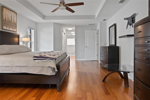 bedroom featuring ceiling fan, multiple windows, and a tray ceiling