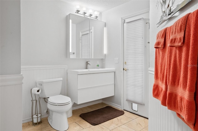 bathroom featuring tile patterned floors, vanity, toilet, and a textured ceiling