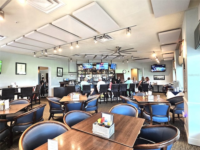 dining space featuring ceiling fan, carpet floors, and bar area