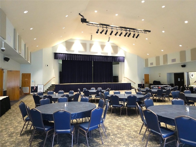 dining room featuring carpet, a towering ceiling, and track lighting