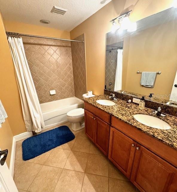 full bathroom featuring toilet, vanity, tile patterned floors, a textured ceiling, and shower / tub combo with curtain