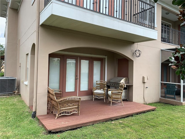 property entrance featuring a deck, central AC unit, a lawn, and french doors