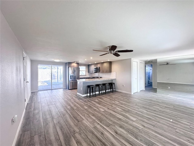 unfurnished living room featuring ceiling fan and light wood-type flooring