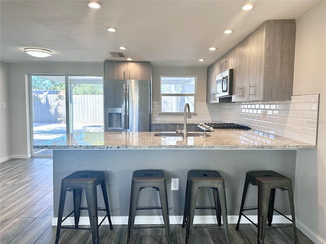 kitchen featuring stainless steel appliances, a kitchen breakfast bar, kitchen peninsula, and sink