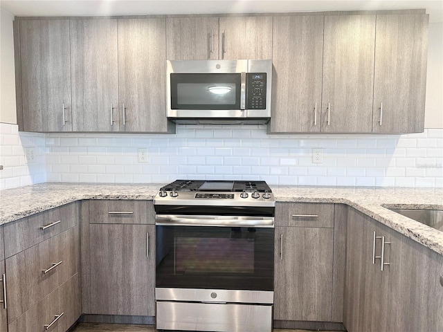 kitchen featuring decorative backsplash, light stone countertops, and appliances with stainless steel finishes