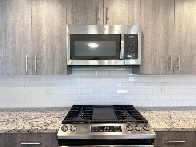 kitchen featuring light stone countertops, decorative backsplash, and stainless steel appliances